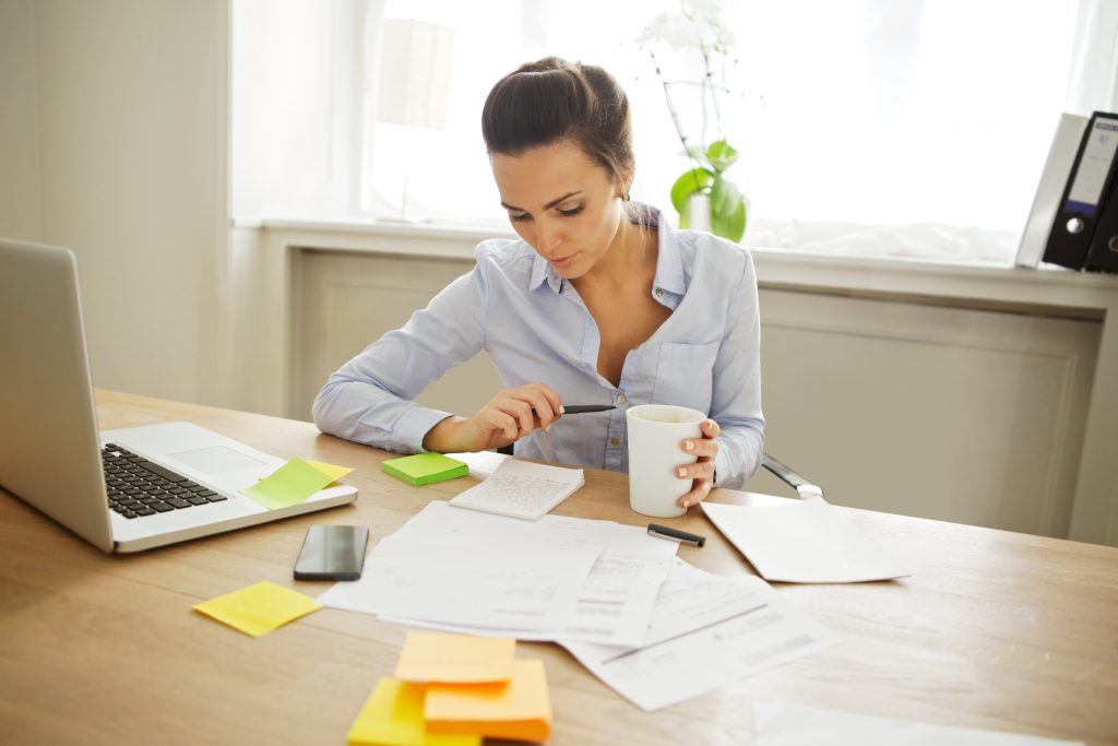A woman working through some papers with a notepad and sticky notes